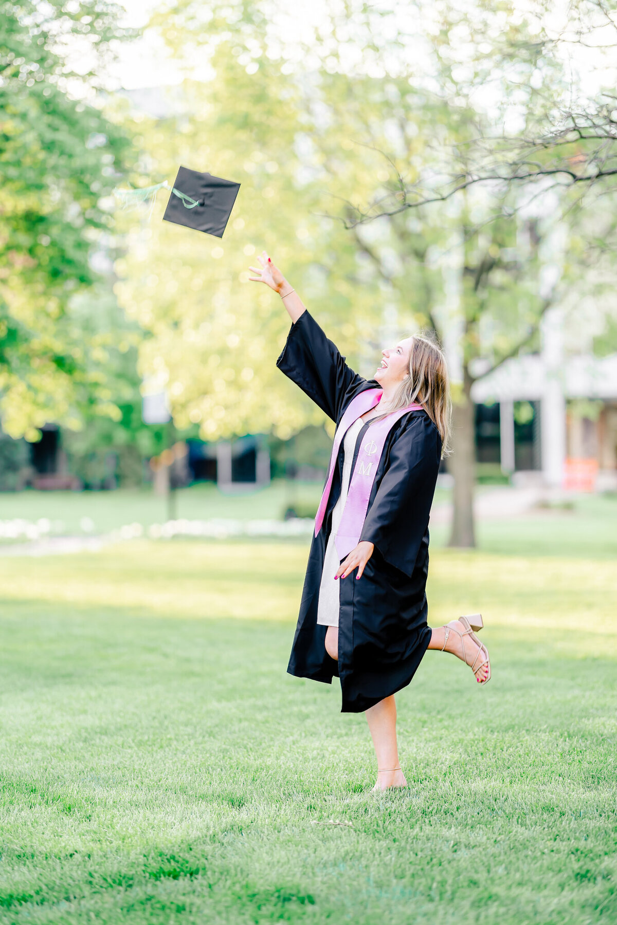 senior girl throwing up her cap while in her gown