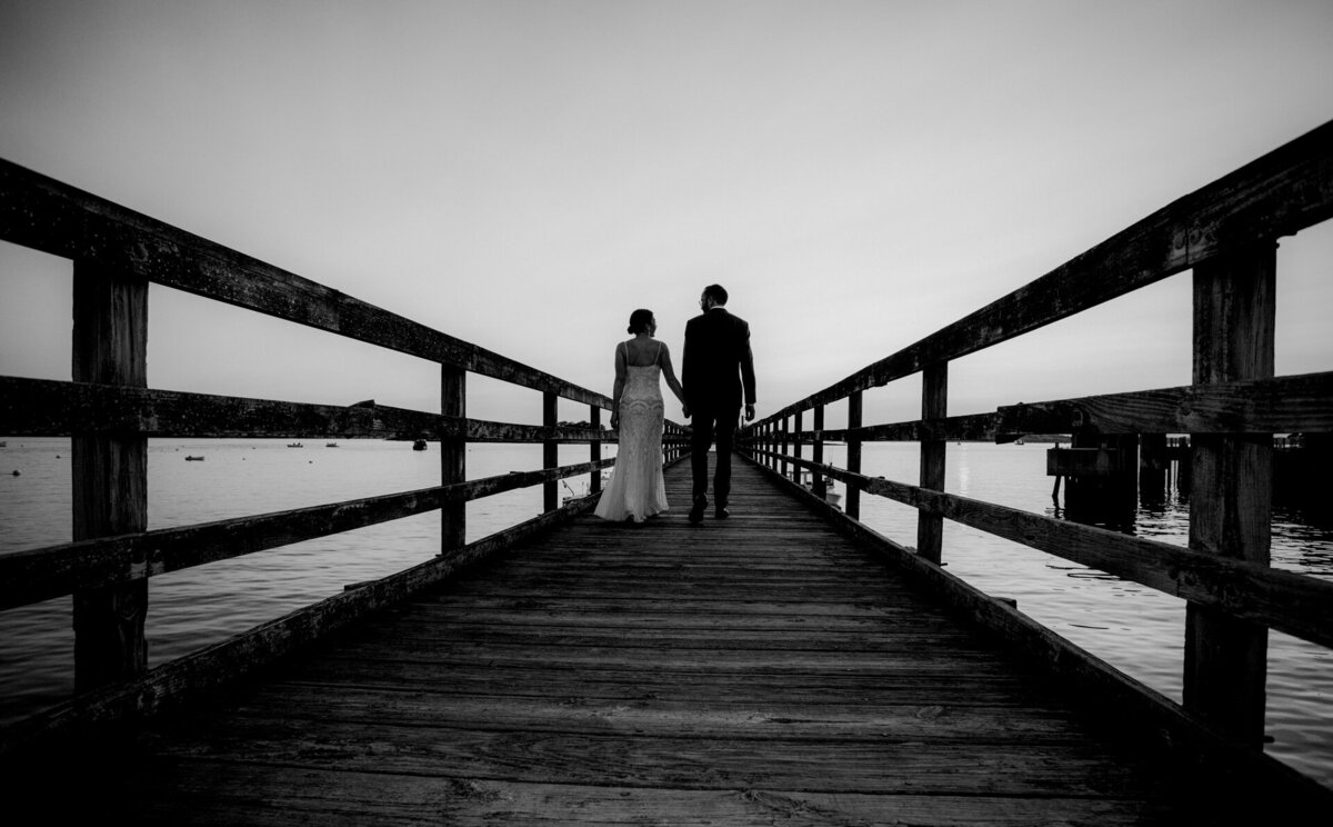 couple on pier overlooking lake at sunset