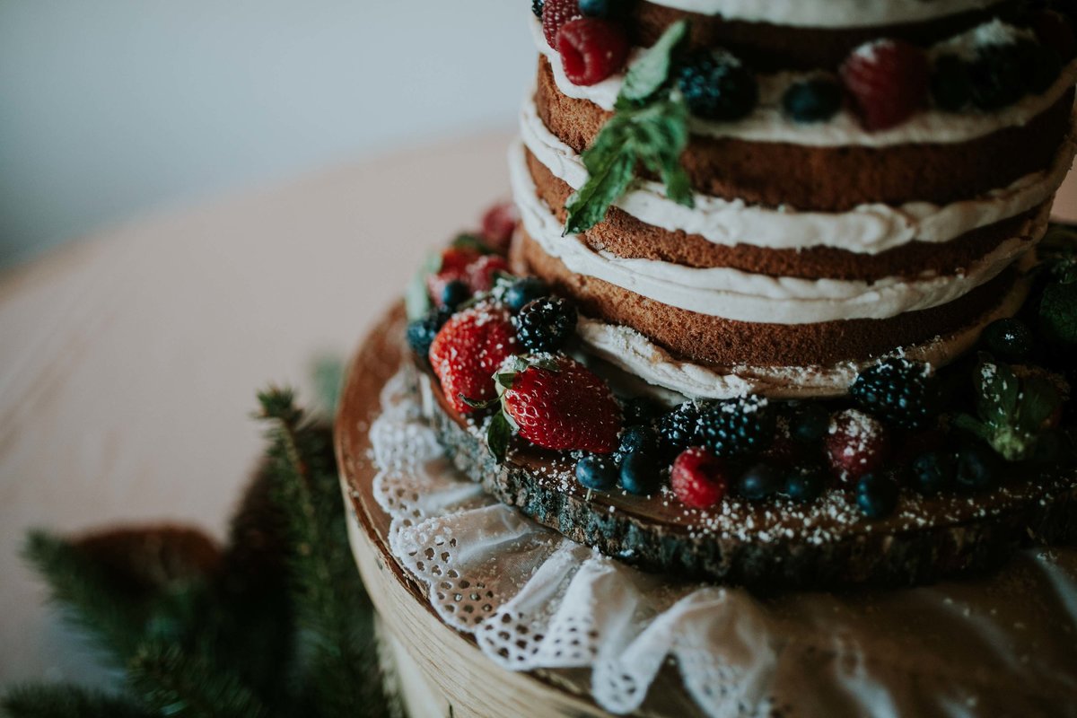 Beautiful berry naked wedding cake  sits on wood and lace at country club wedding in indianapolis
