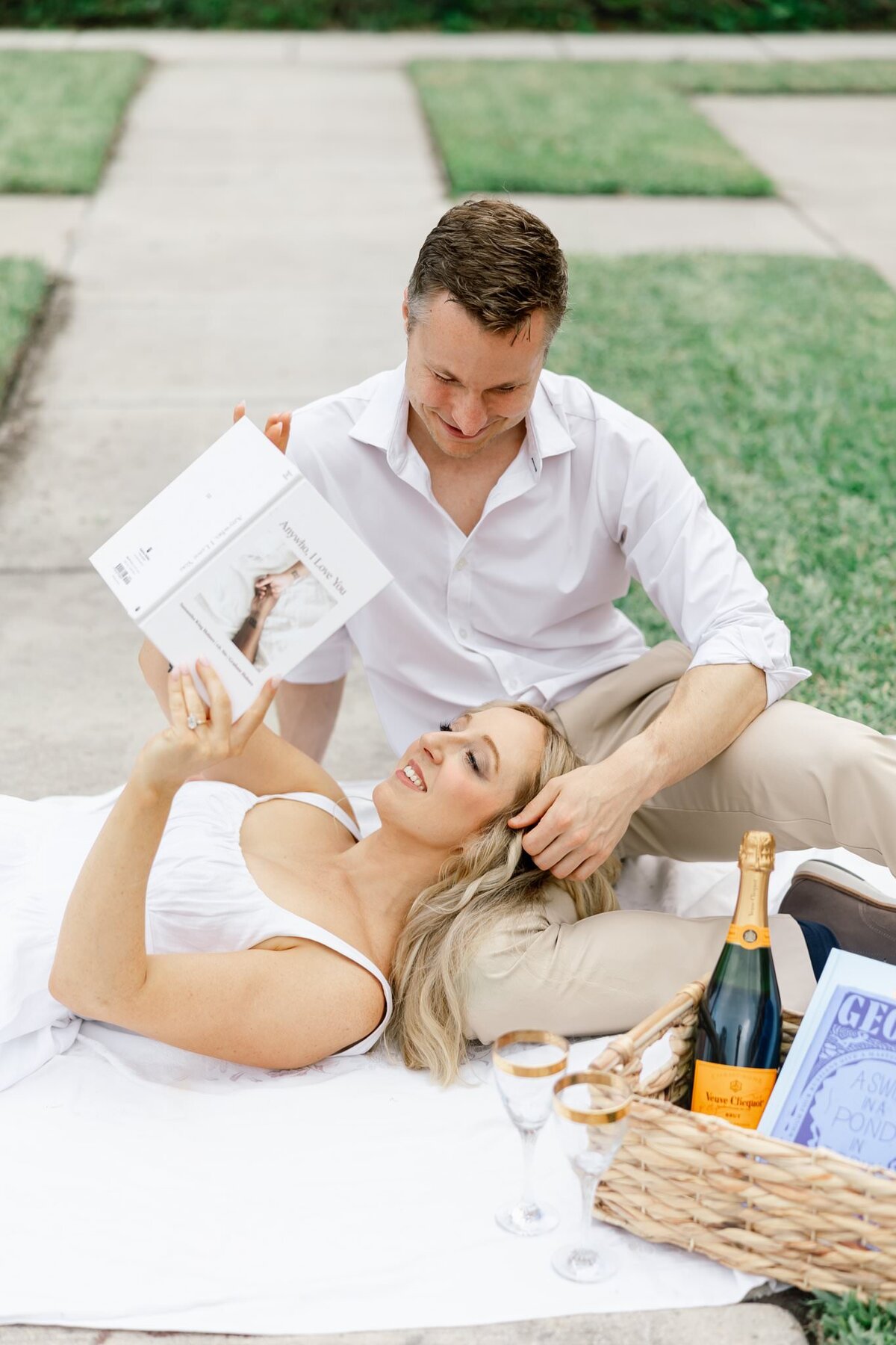 man caressing woman as she reads laying on picnic blanket taken by wedding photographers in orlando fl