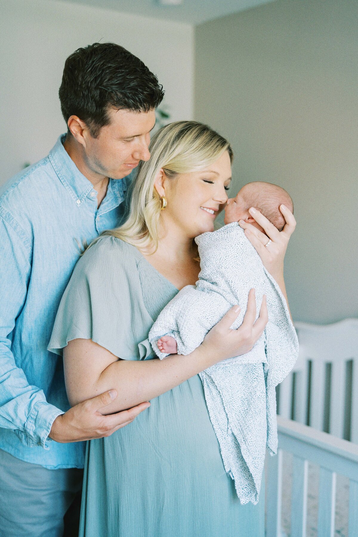 mom and dad admiring newborn son in nursery