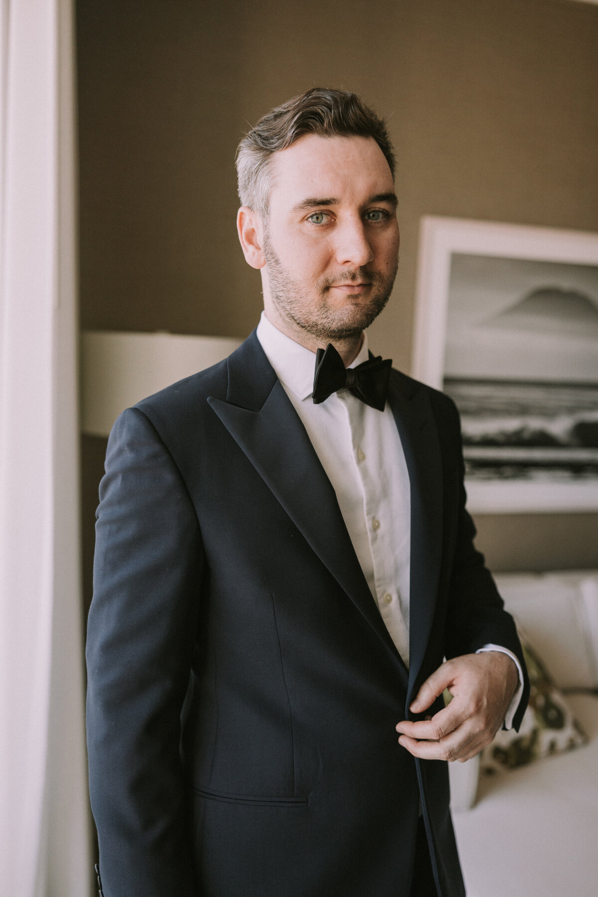 Groom wearing bowtie portrait in hotel room