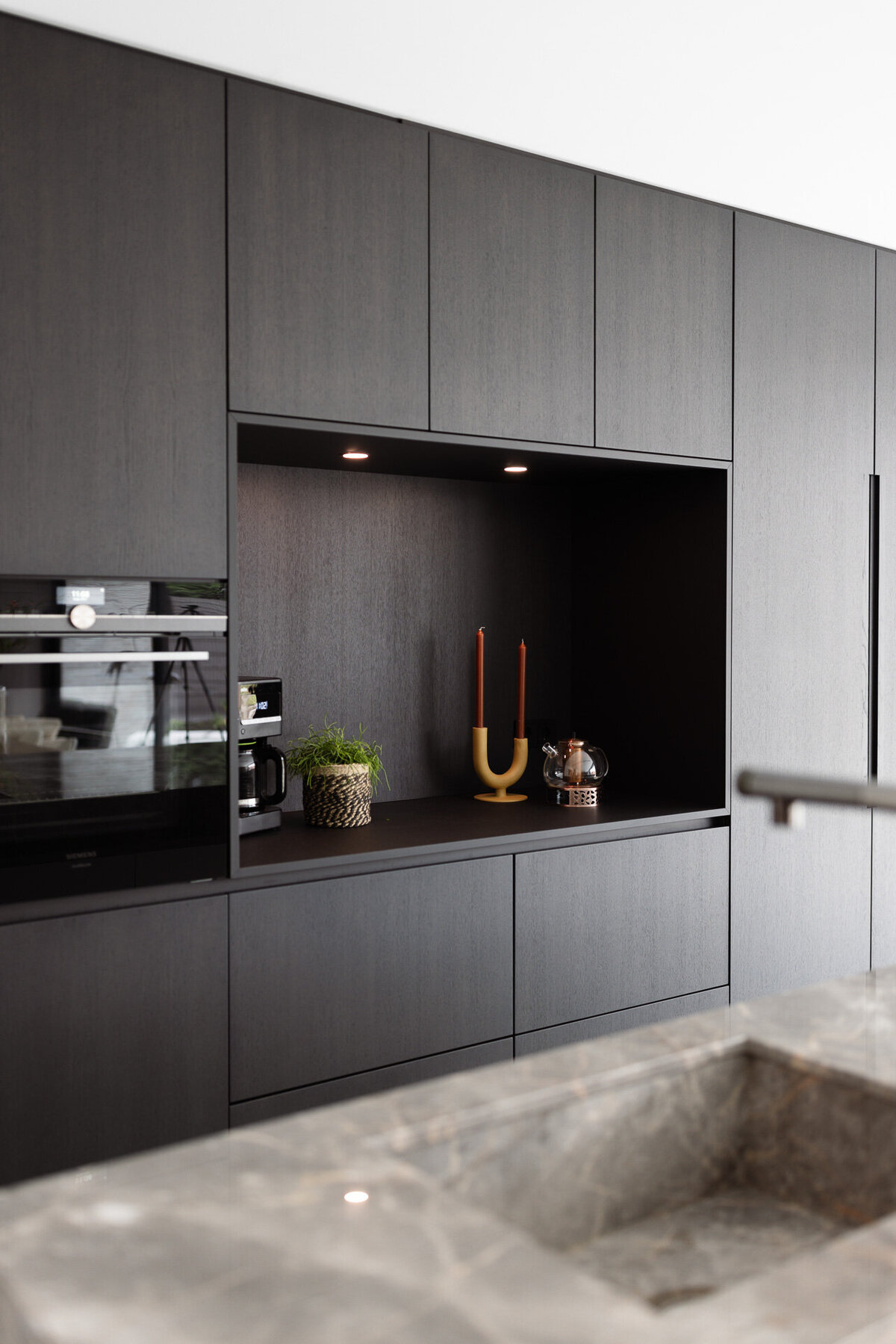 Een strakke zwarte keuken met een contrasterend marmeren werkblad voor een high-end uitstraling.