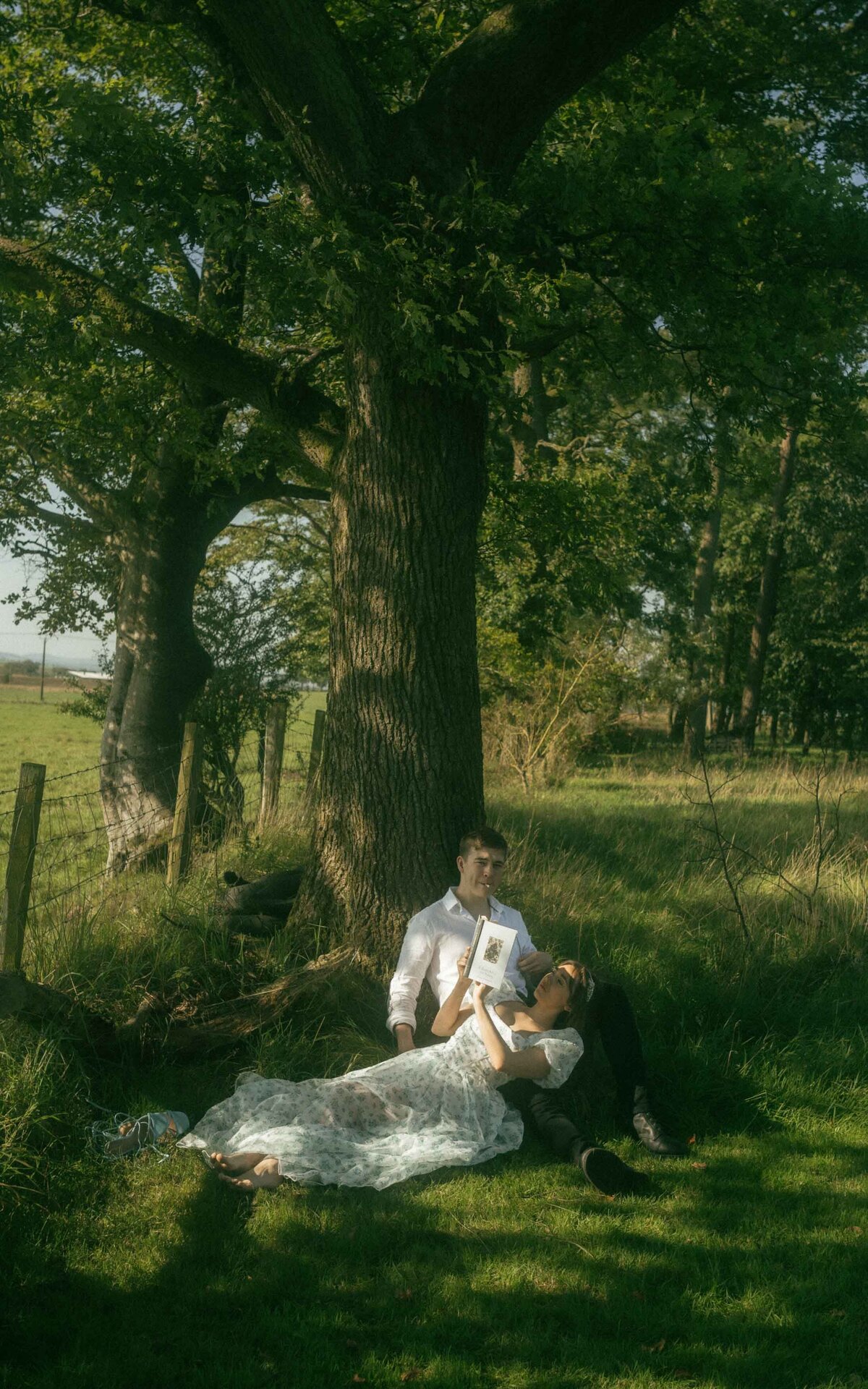 Capture serene romance with this intimate couple photoshoot, seated together under a tree. A timeless moment of connection and tranquility perfect for your wedding inspiration