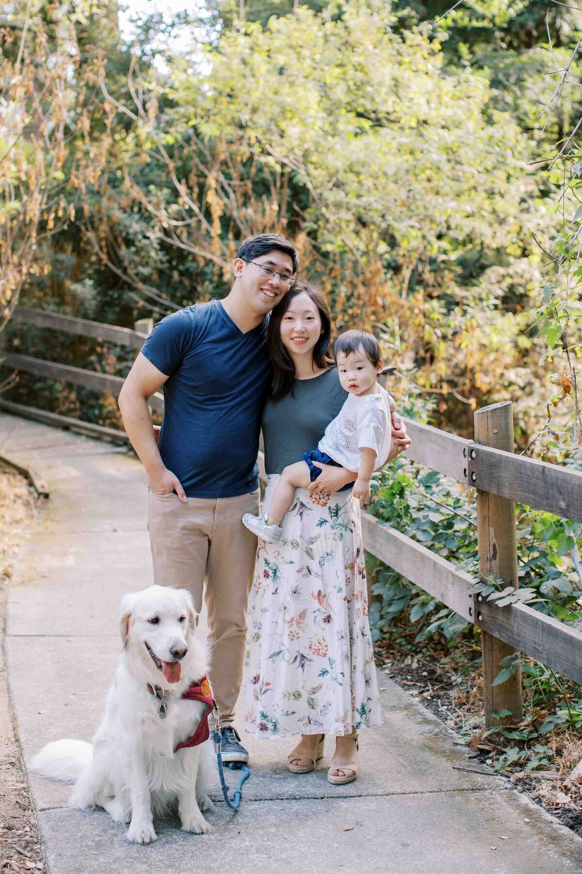 family of 3 smiling with their golden retriever