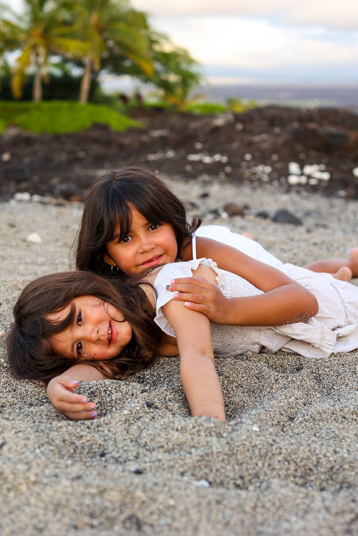 Two girls laying on the beach looking at big island family photographer