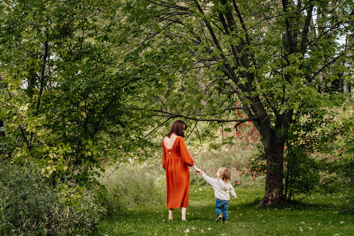 A mom and child walk in the woods.