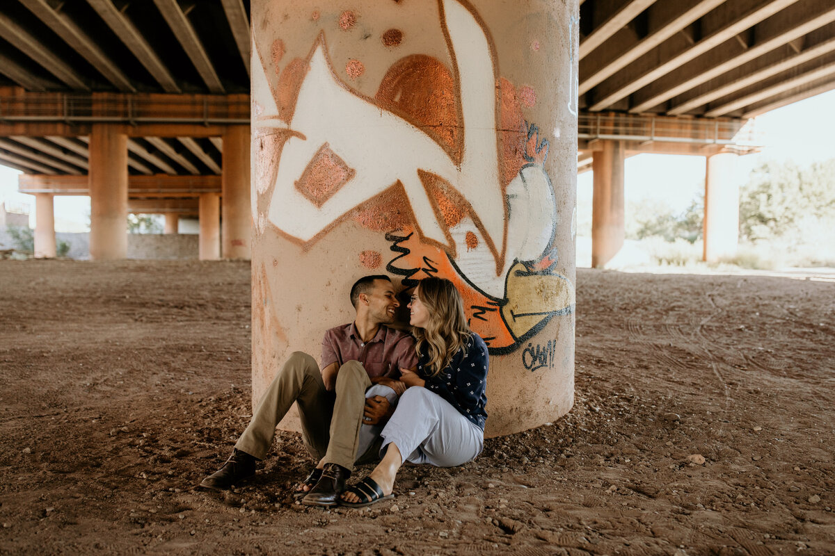 couple sitting against a pillar under an overpass in Albuquerque