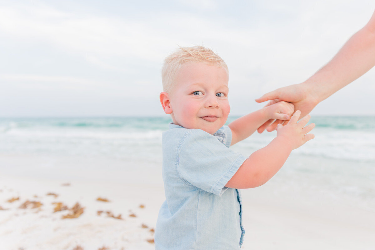 little boy on Pensacola Beach holding daddy's hand