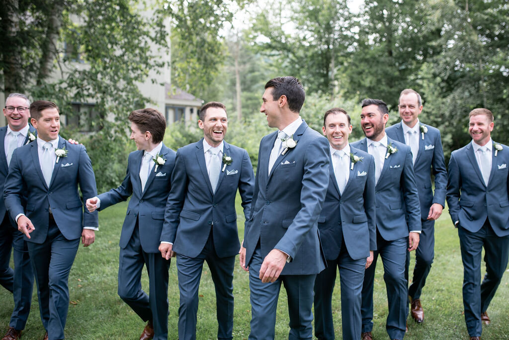 A candid shot of groomsmen dressed in navy suits and white button downs.