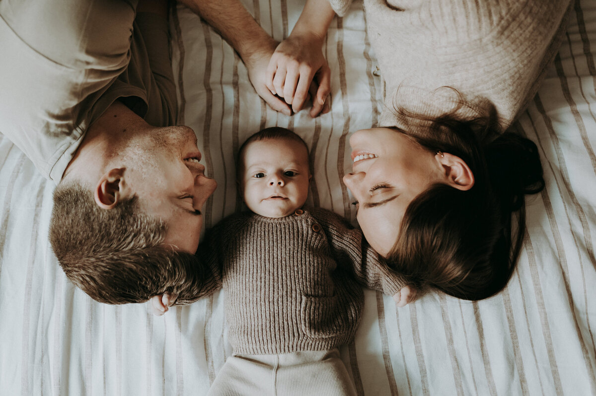 Bovenaanzicht foto van een koppel met hun baby op het bed