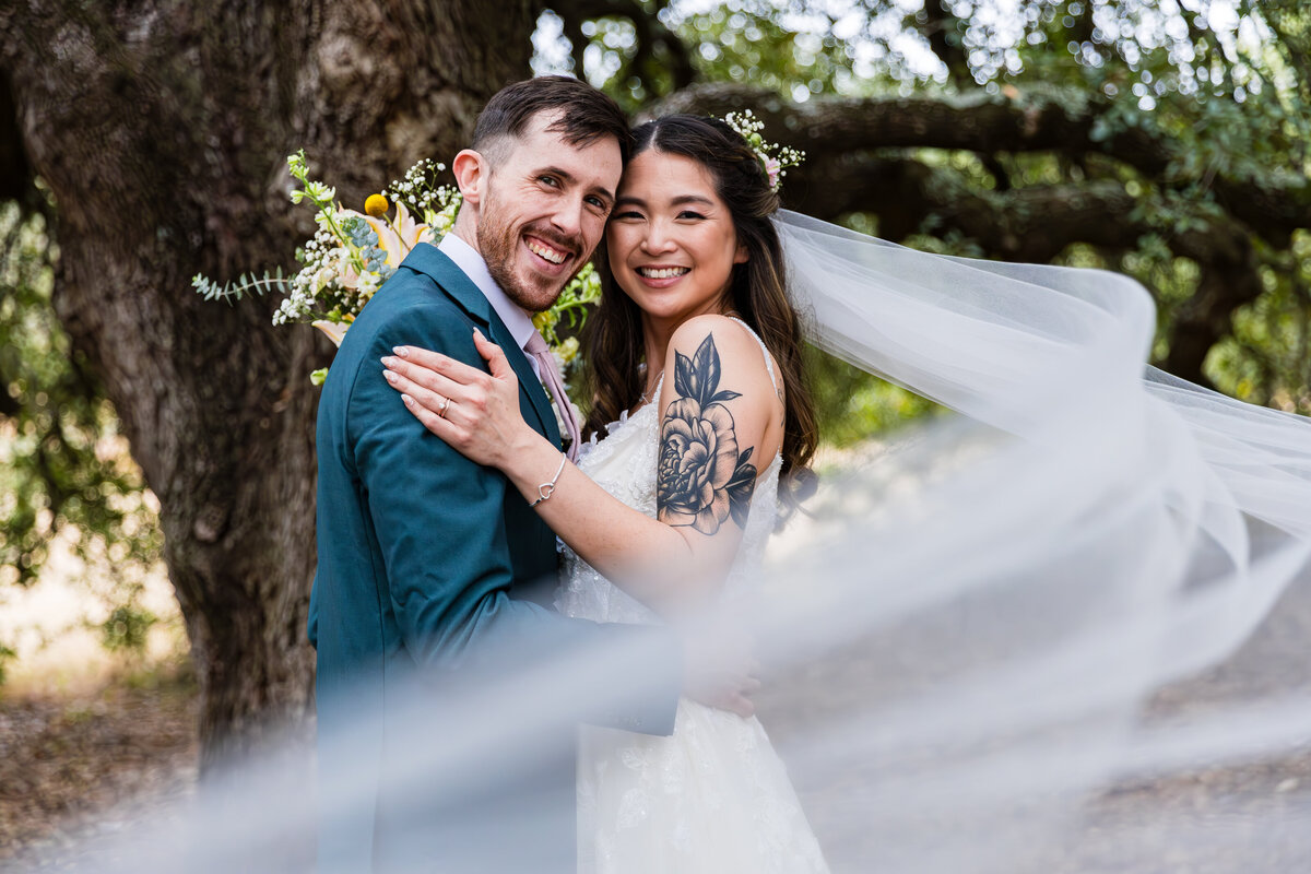 dallas fort worth wedding photographer, couple smiling at camera with the veil in the foreground creating a stunning couples portrait