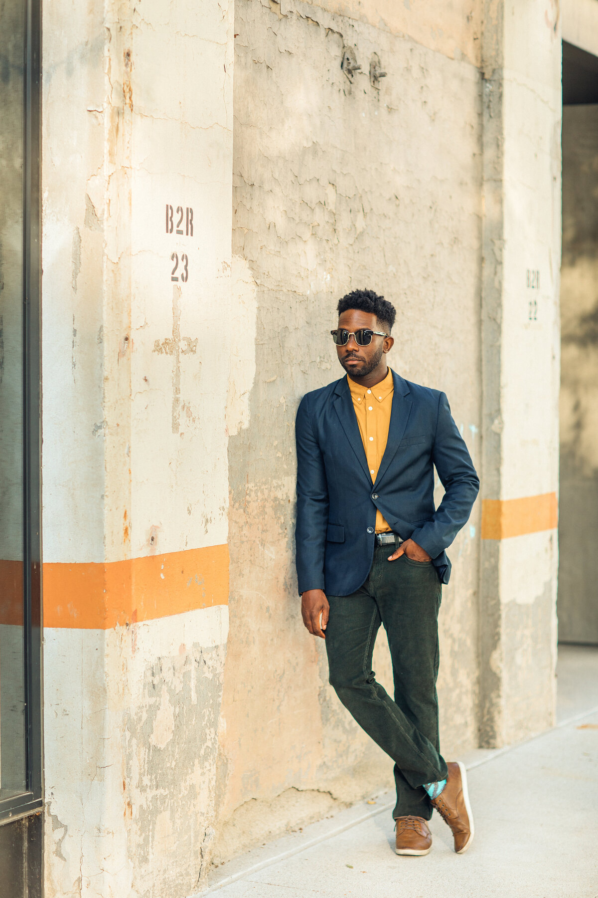Portrait Photo Of Young Black Man Leaning Against a Wall With One Hand In His Pocket Los Angeles