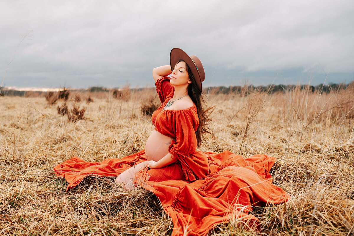Springfield MO maternity photographer captures side view of pregnant mom kneeling in field