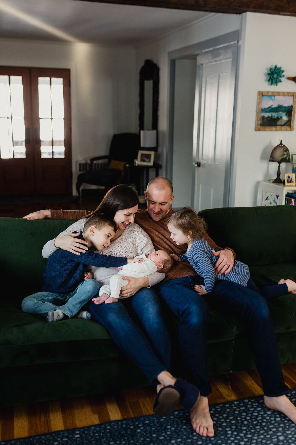 family photoshoot of a family snuggles on couch with newborn