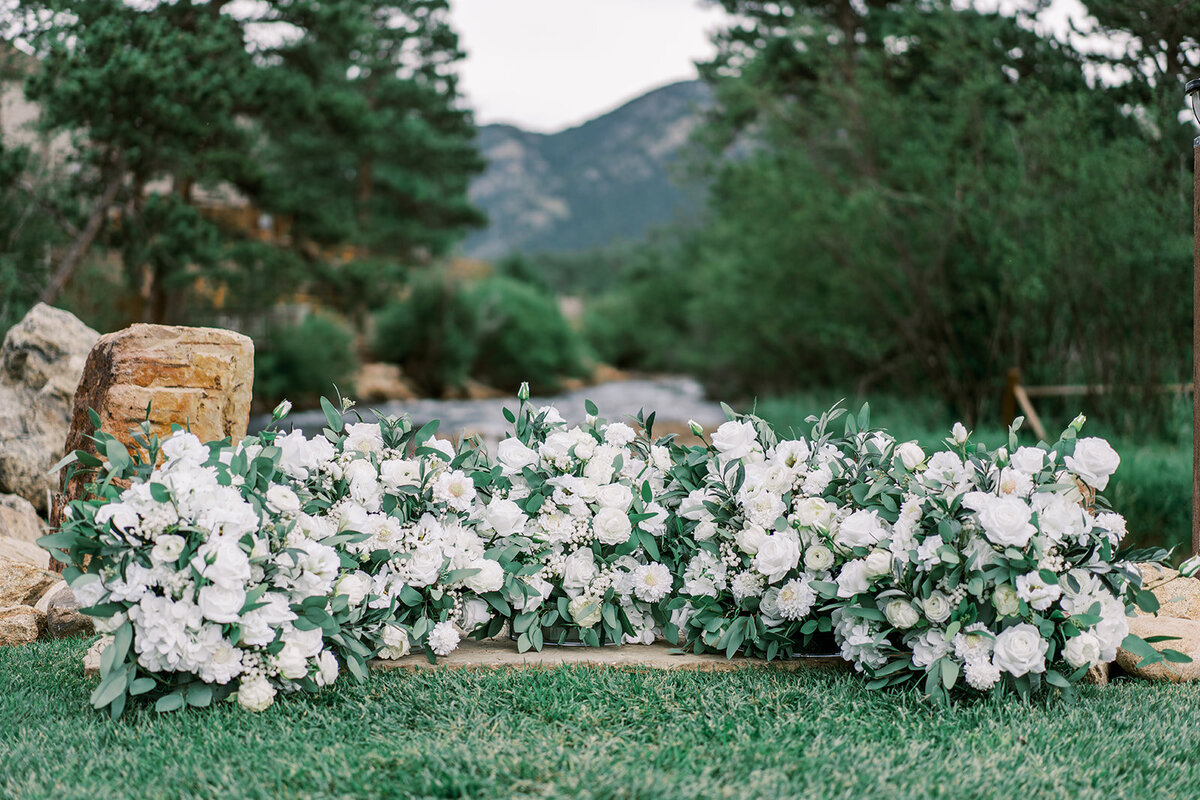 Lush white flowers with greenery making a ground arch as the center for a ceremony at the Landing in Estes Park.