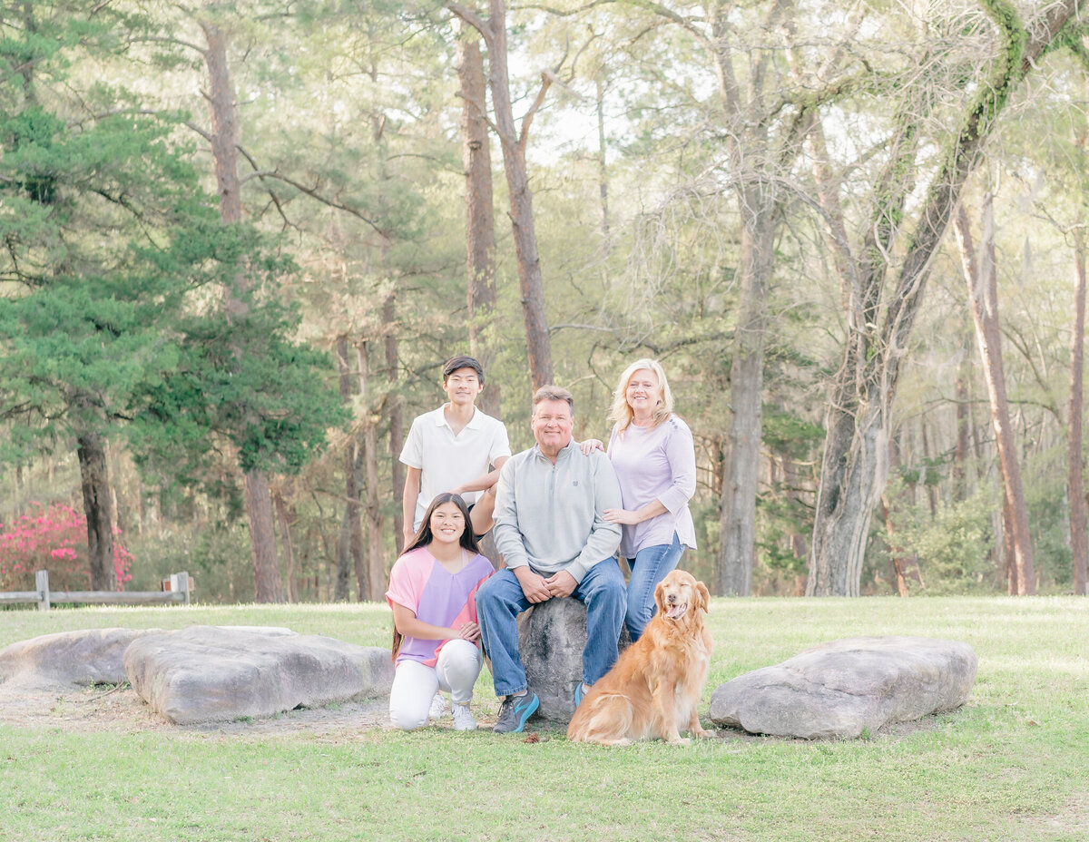 family sitting on rock with dog during son's senior picture photo shoot at a local state park