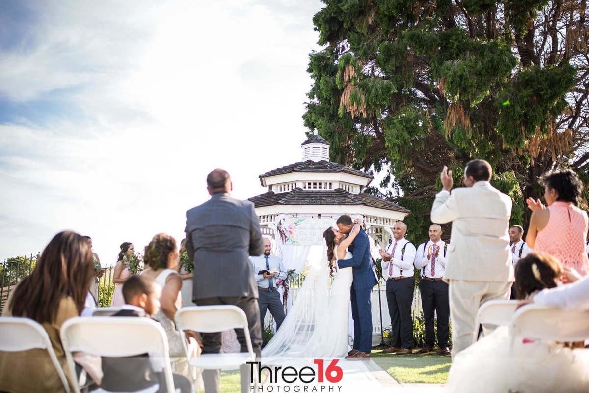 Bride and Groom's first kiss as guests stand and applaud