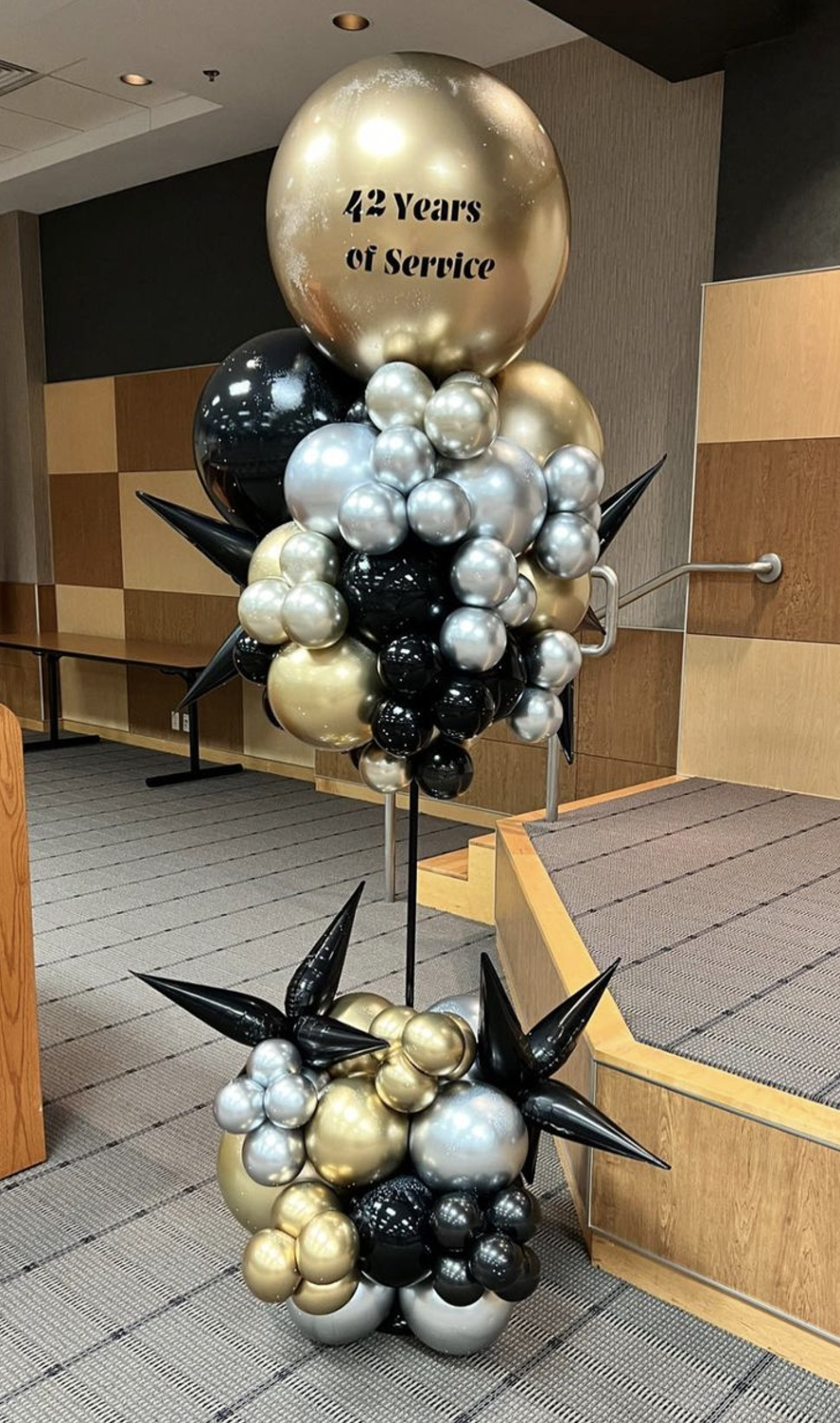 Black, gold, and white balloon decor for elegant indoor event setups.