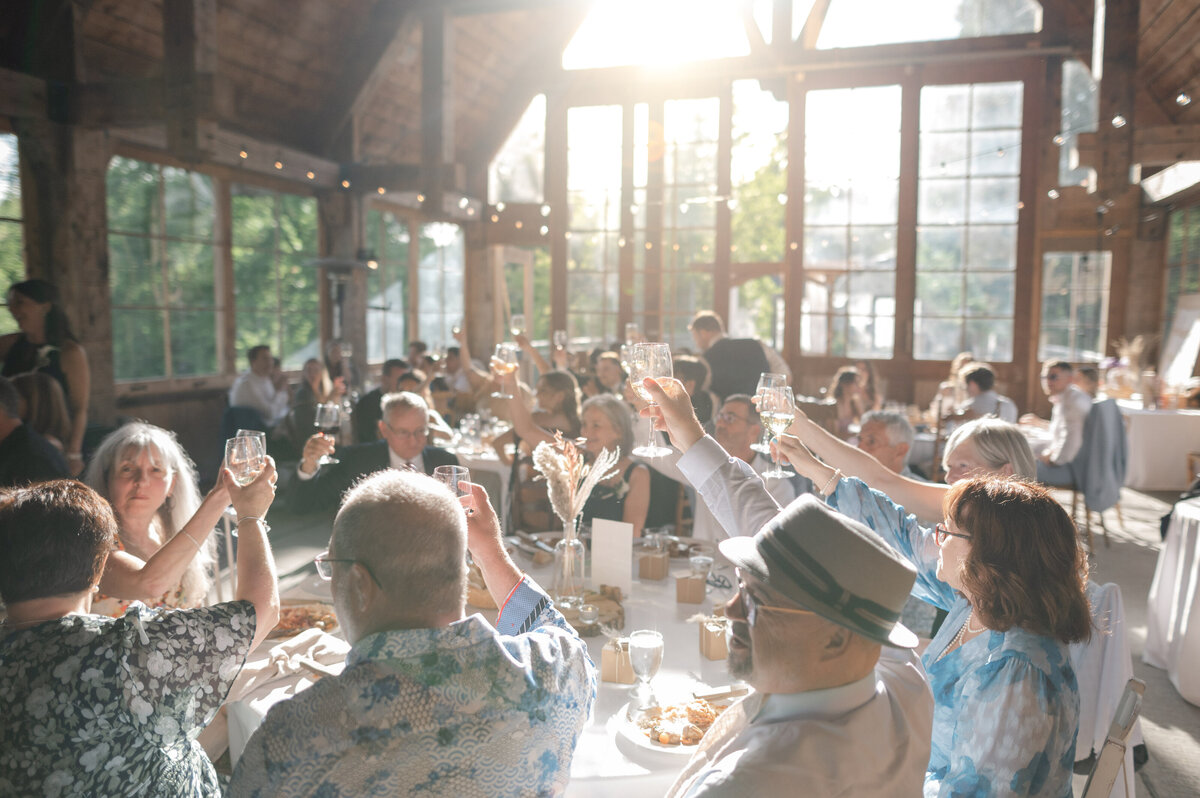 Moment de célébration alors que les convives lèvent leurs verres pour honorer l’amour des mariés faisant leur entrée en salle de réception au Pont Couvert de La Conception, dans les Laurentides, ambiance festive et émotive d’un mariage inoubliable