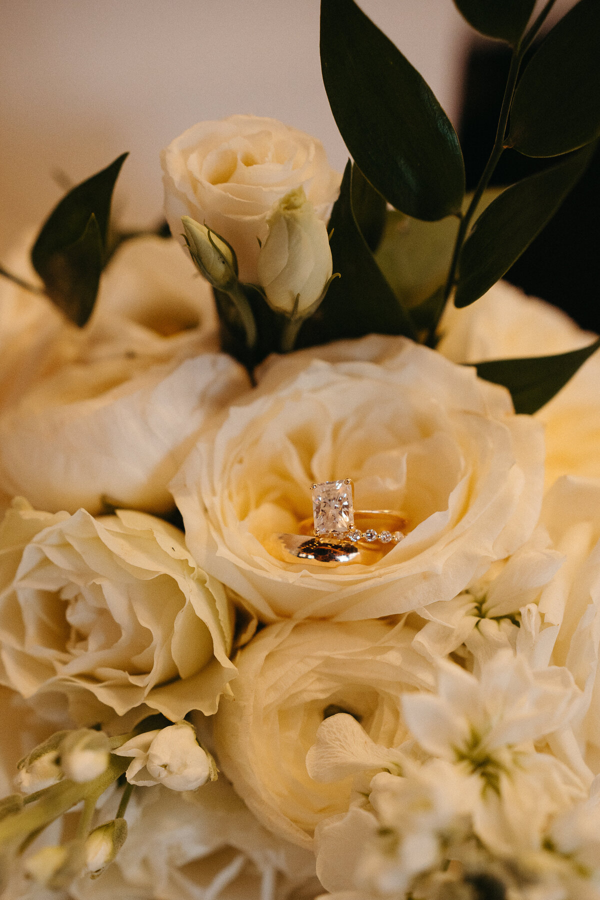 a close up image of a diamond engagement ring sitting in a boquet of white roses