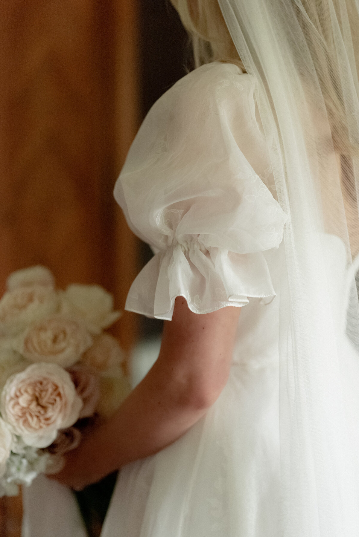 Bride wearing puff sleeve patterned silk wedding dress with veil and sweetheart back and holding peony wedding bouquet in the Bridal Suite of Cromlix House, Scotland.