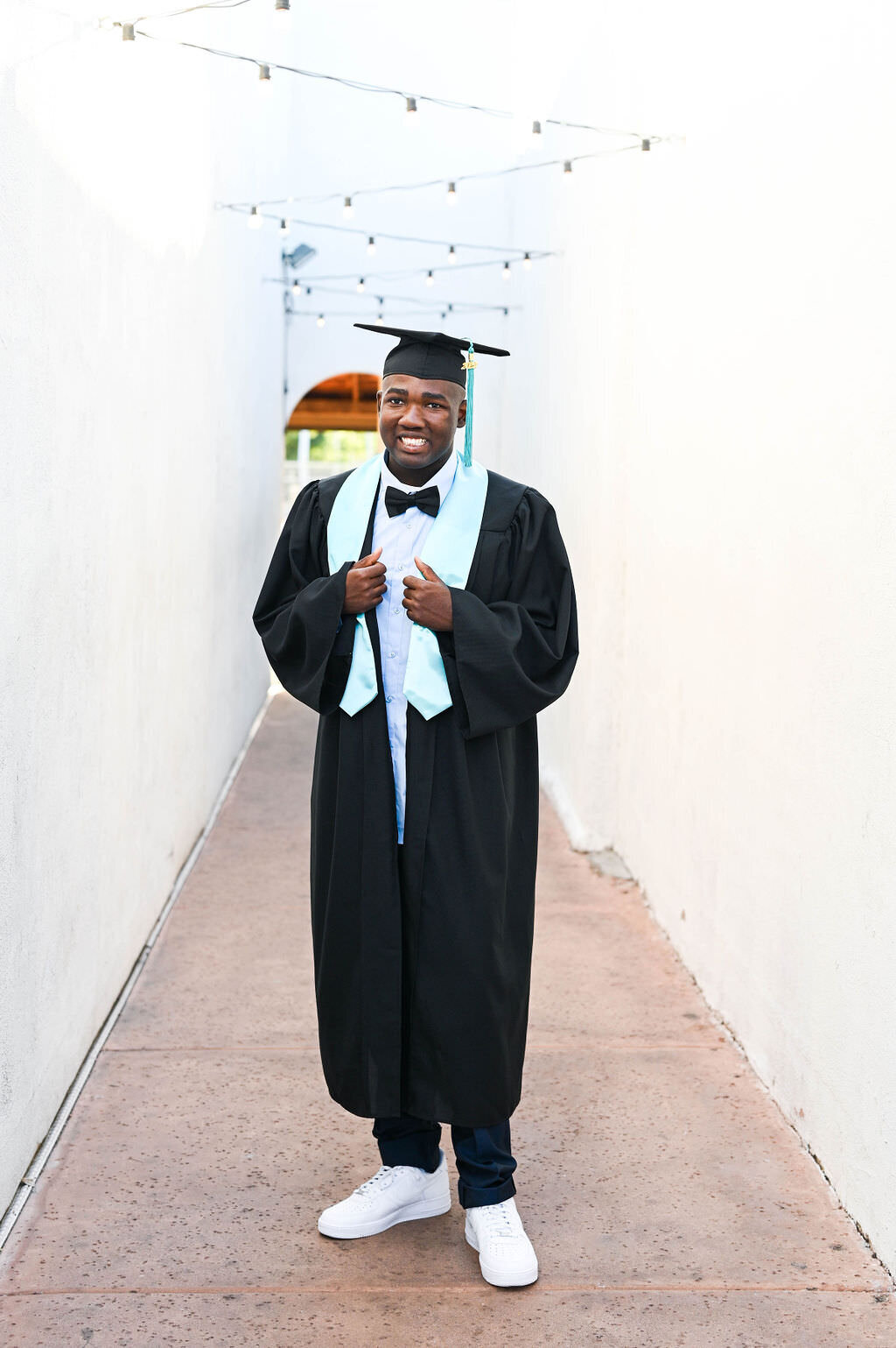 A boy in a graduation cap and gown smiling.