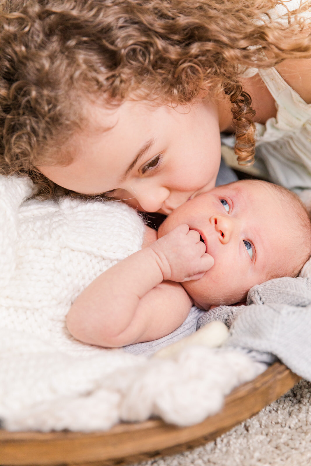 toddler sibling kissing newborn baby