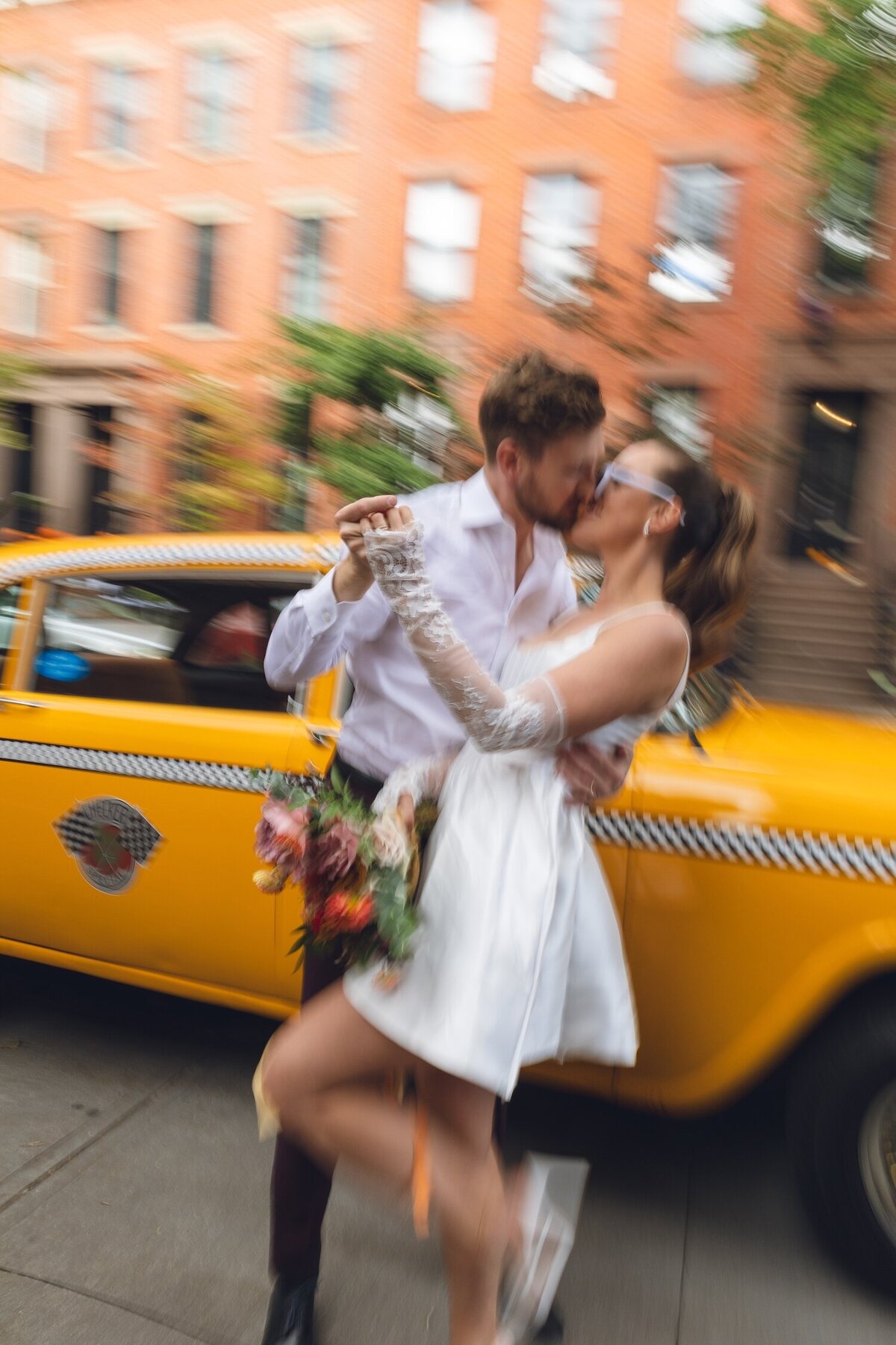 Bride smiling while groom lifts her near vintage yellow cab