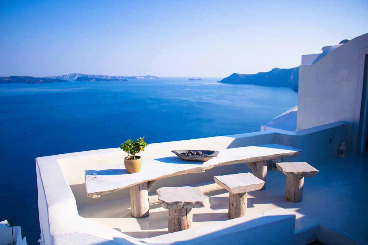 A driftwood table sits on a sea view balcony in greece.