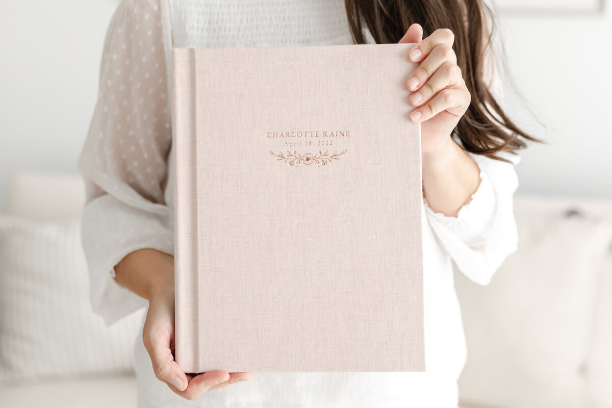 woman hold pink linen-covered family photo album