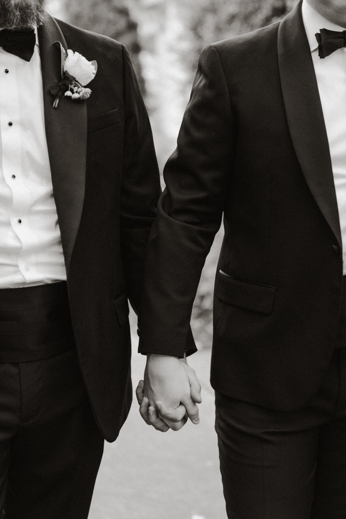 A close up of two grooms holding hands.