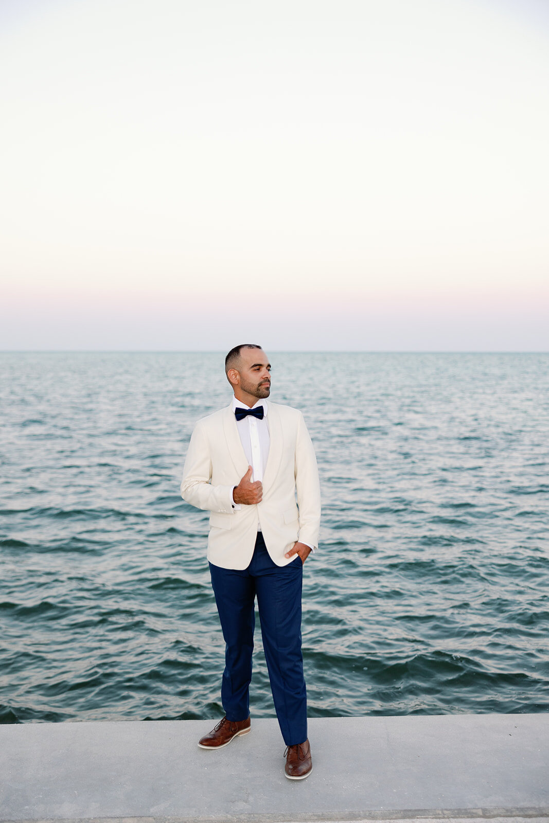 Rafael in a cream tuxedo stands against the Islamorada ocean backdrop, exuding timeless elegance at La Siesta Marina Resort.