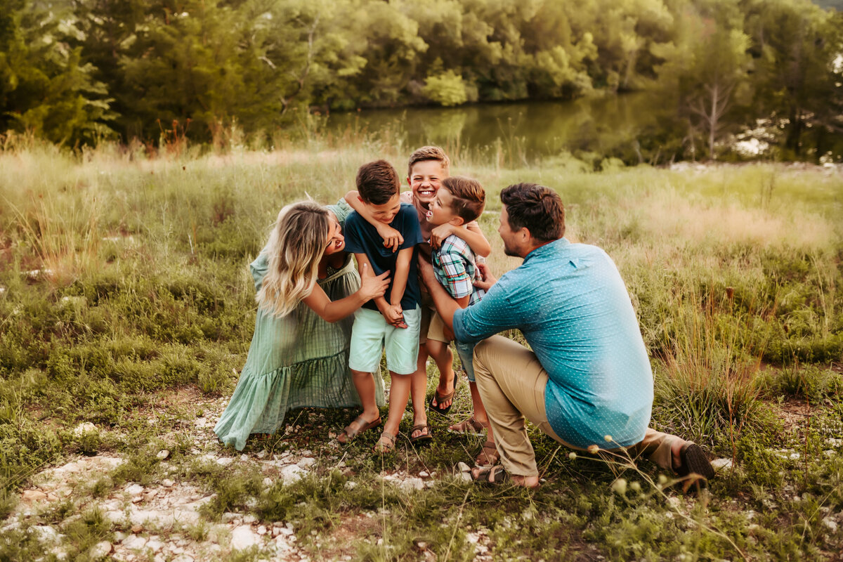 Mother and Father tickle their three children while the giggle at each other