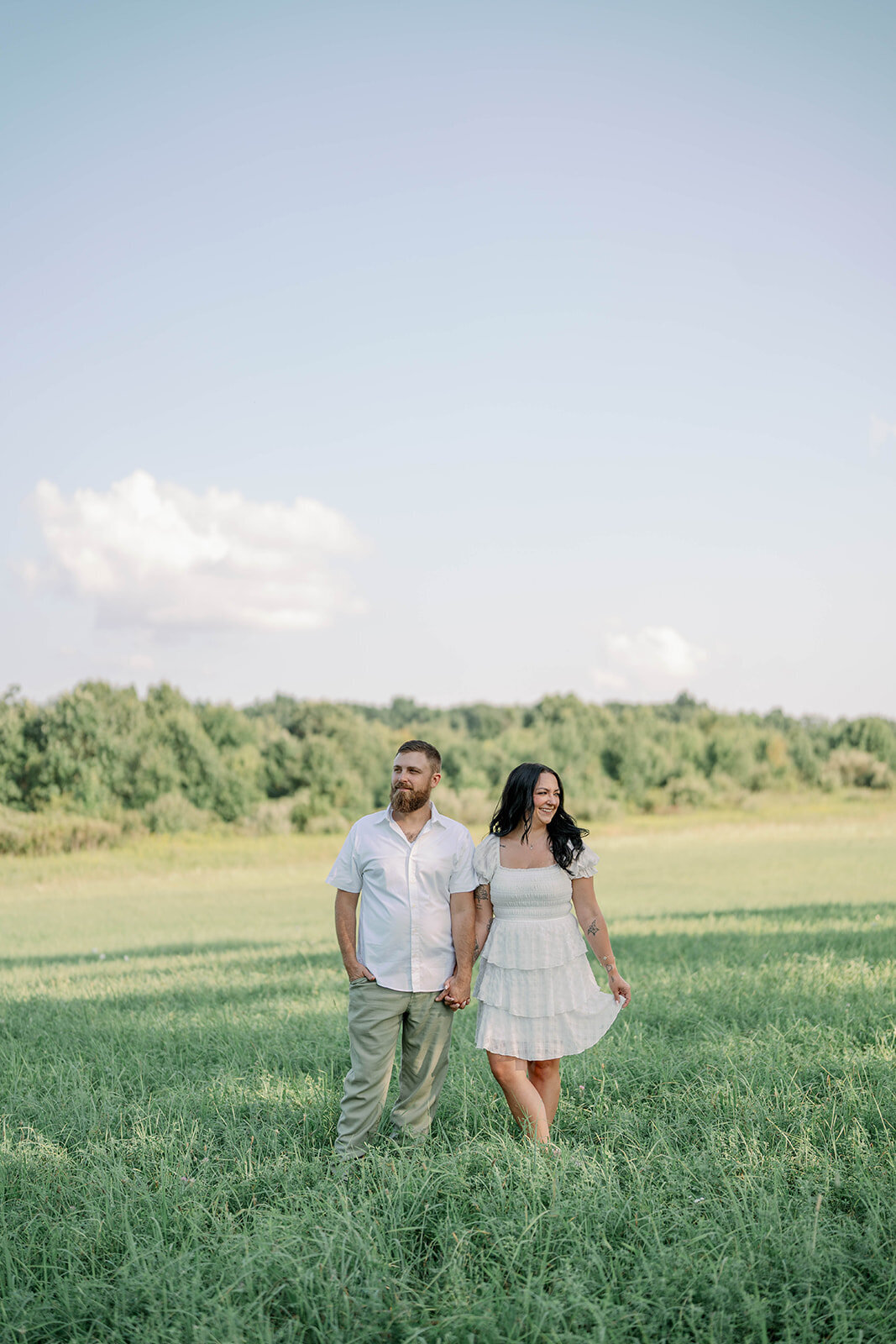 Kali and Joe standing together in tall grass during their engagement session on a private property outside Detroit.