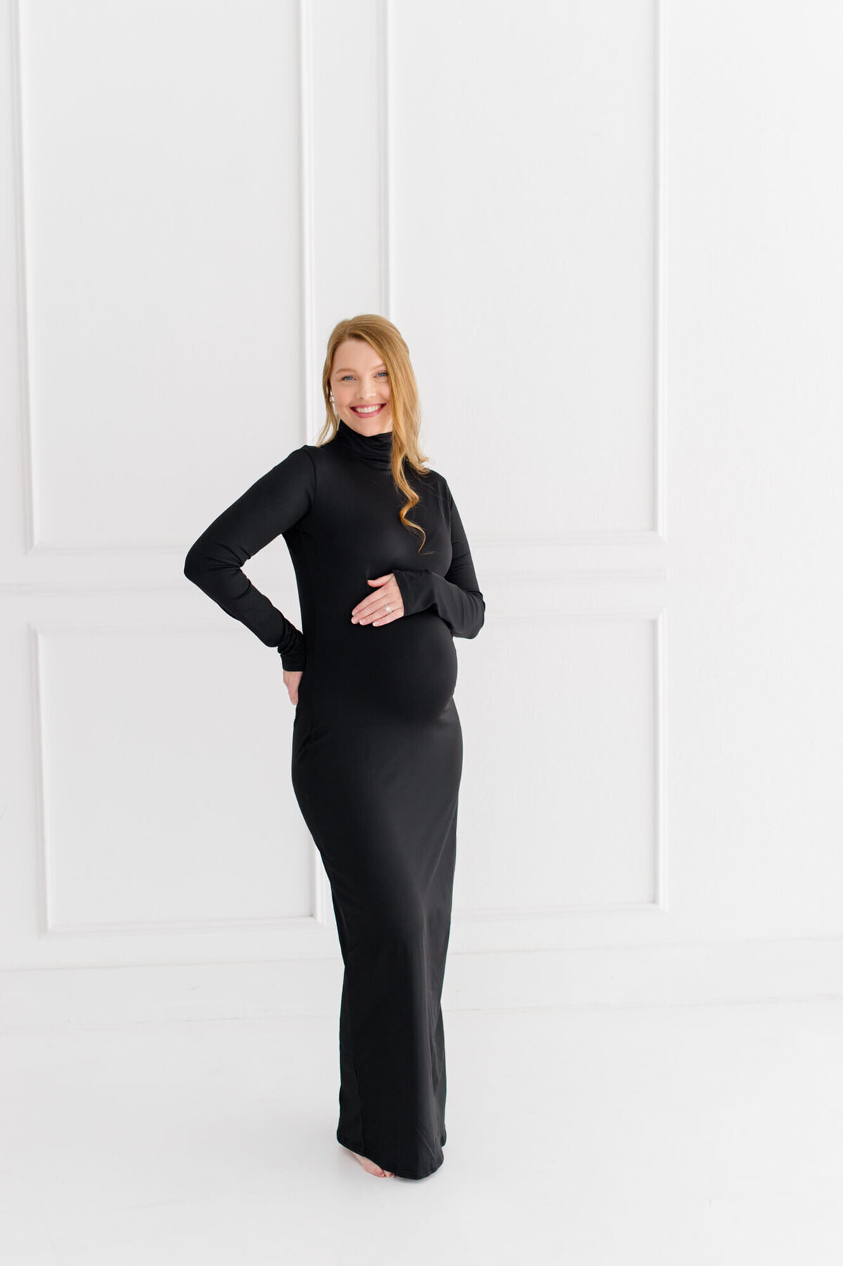 Orlando maternity photographer captured a pregnant mother holding her belly in the studio wearing an elegant black dress