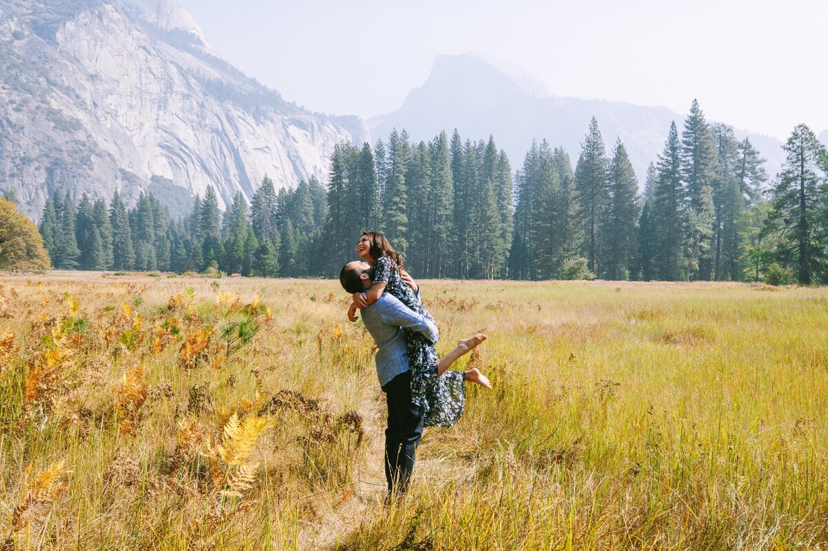 man picks up woman in meadow