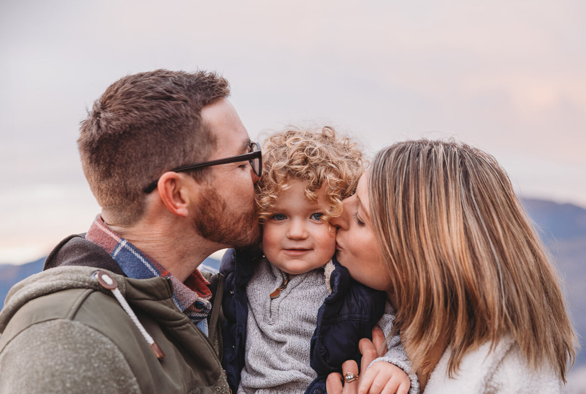 mum and dad kissing son on the cheek while having fun during their family photoshoot in wanaka captured by Bie