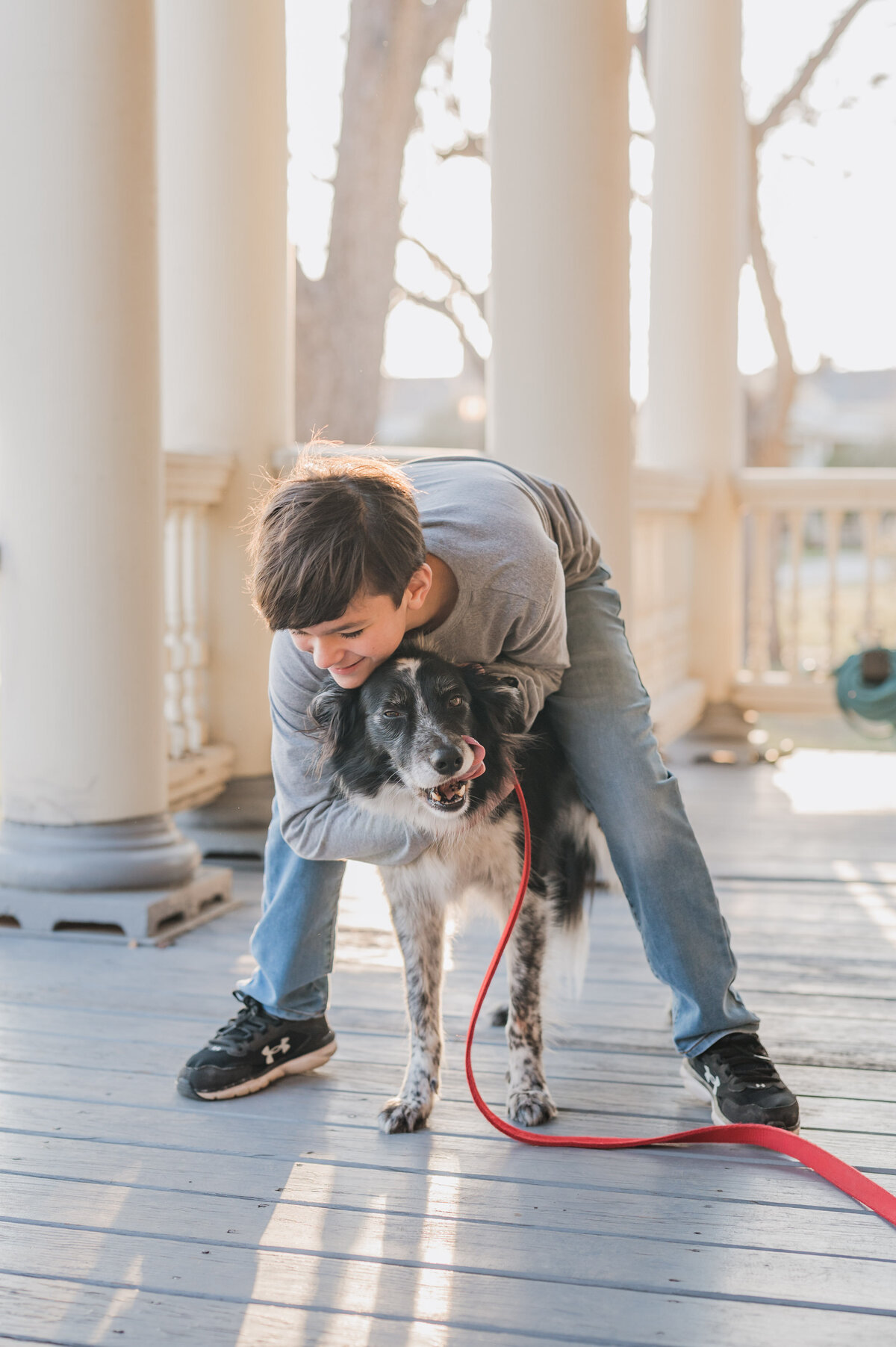 San Antonio family photography of a boy hugging his dog on their front porch.