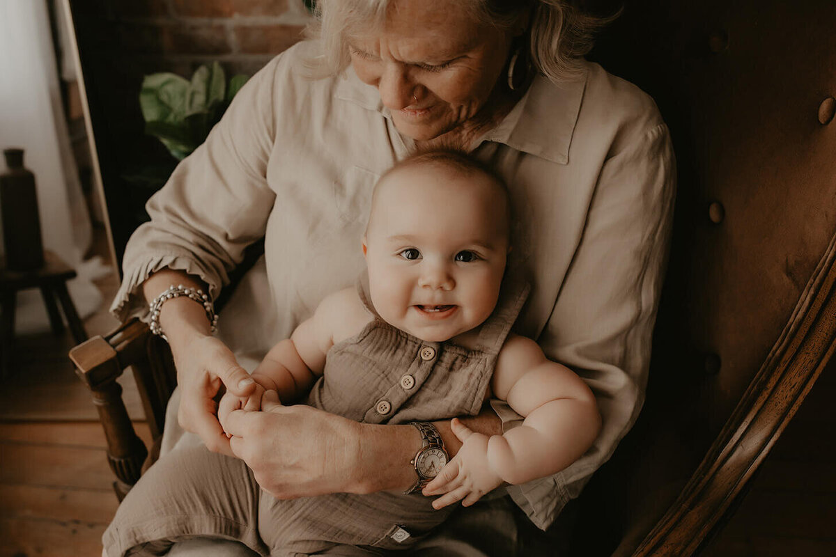 A grandma looks down at her grandson while holding him on her lap