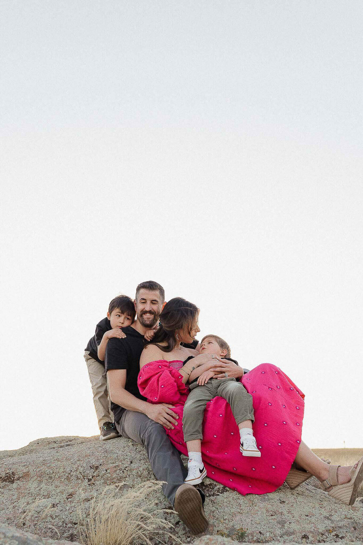 Family embracing tenderly on a rock during sunset in Cleveland.