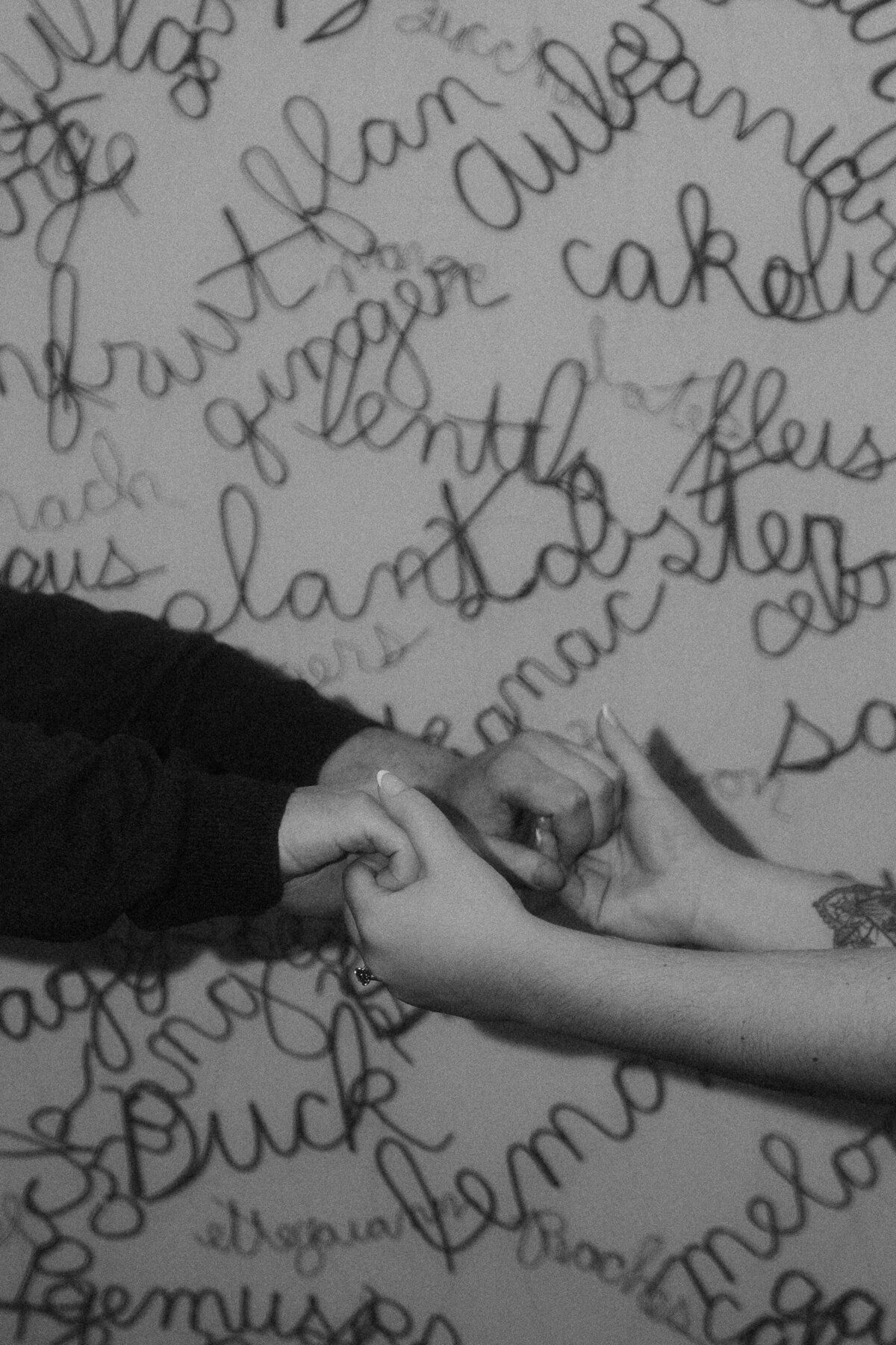 close up of couple holding hands, cursive words in background