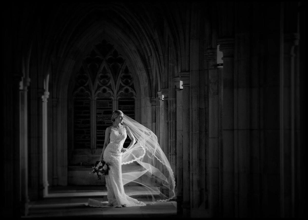 A bride standing in a hallway with her veil floating around her