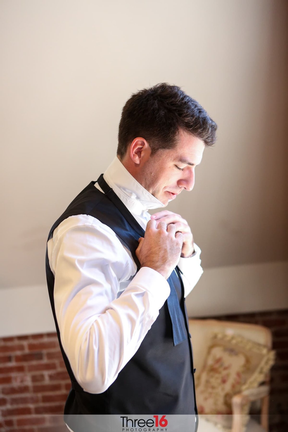 Groom putting on his tie before the ceremony