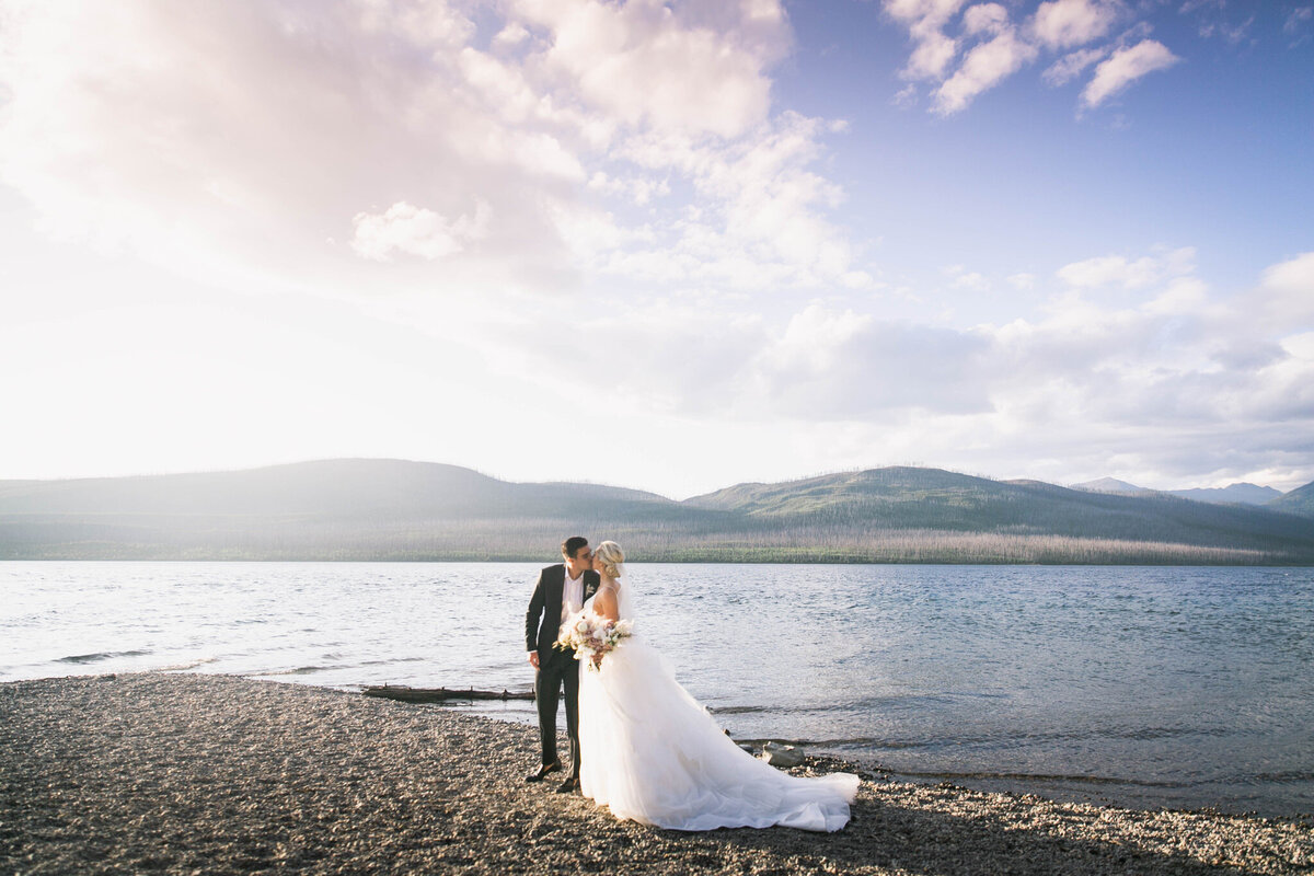 bride and groom standing by lake