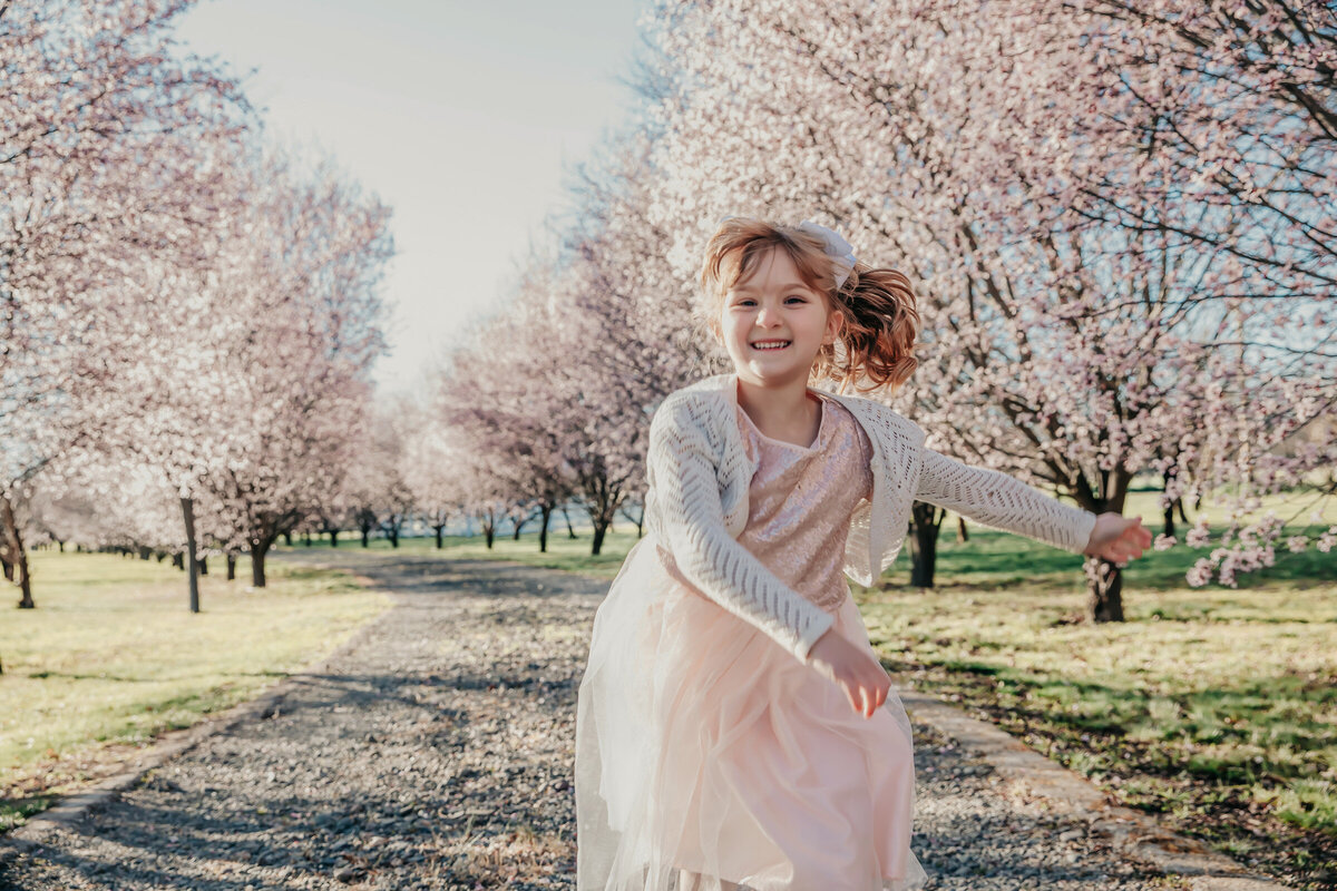 little girl running in cherry blossoms