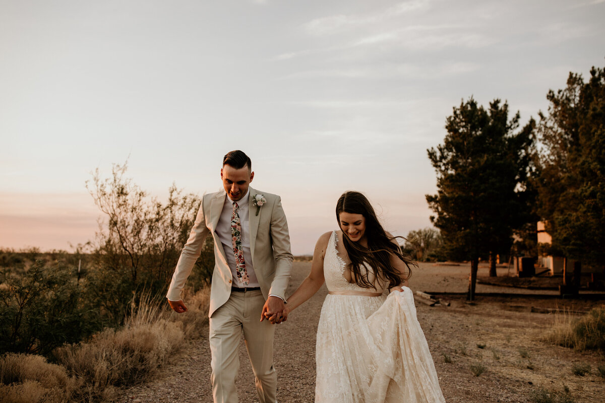 bride and groom running  in the desert at sunset