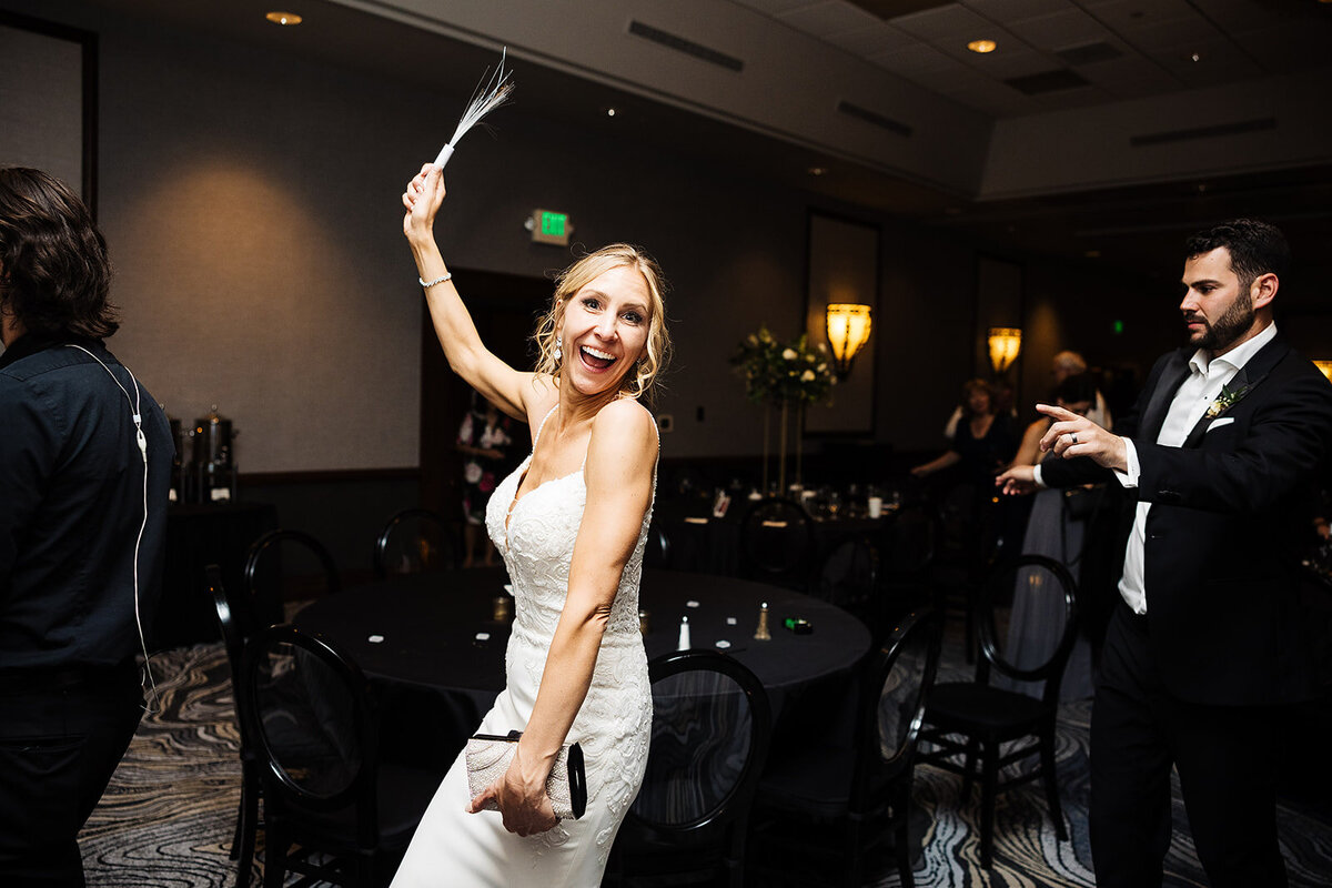 Bride holds a glow stick and dances on her way to her after party at her wedding reception.