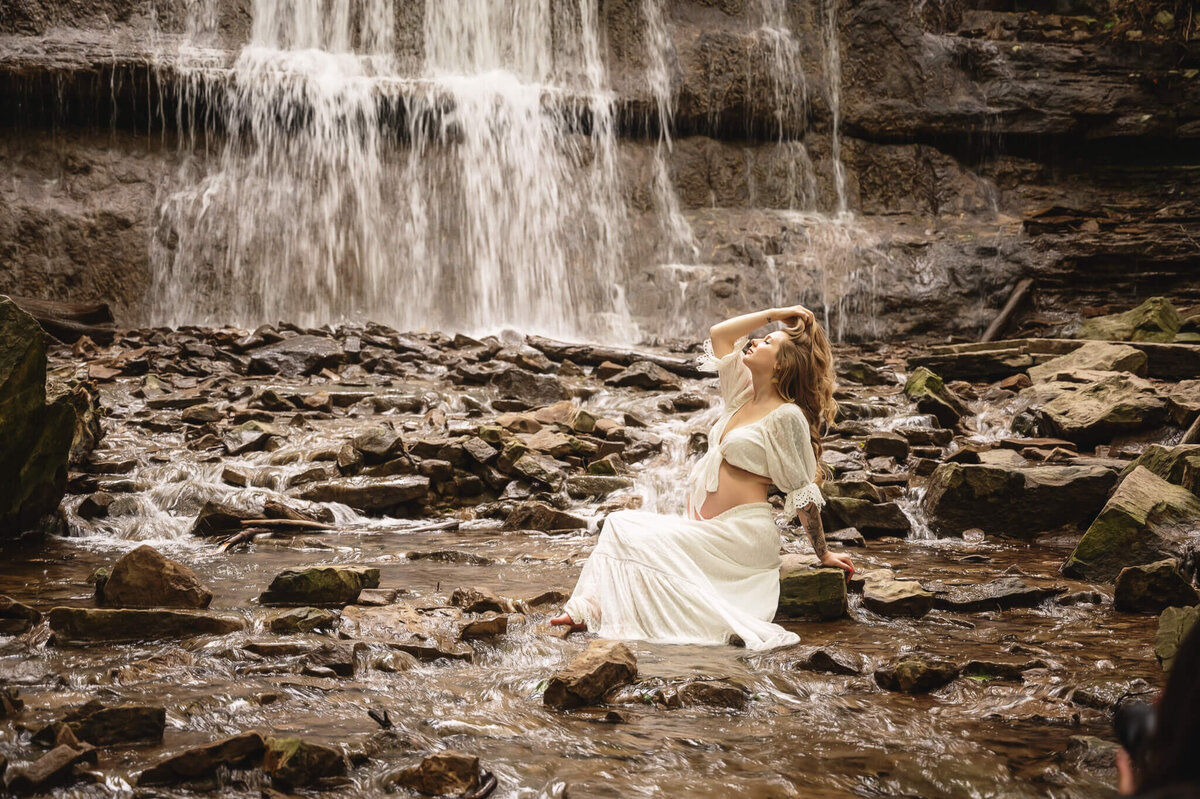 Cascading waterfalls in Hamilton as a background for this expectant mom in white for her Greater Toronto Maternity Photo shoot, Tamara Danielle.