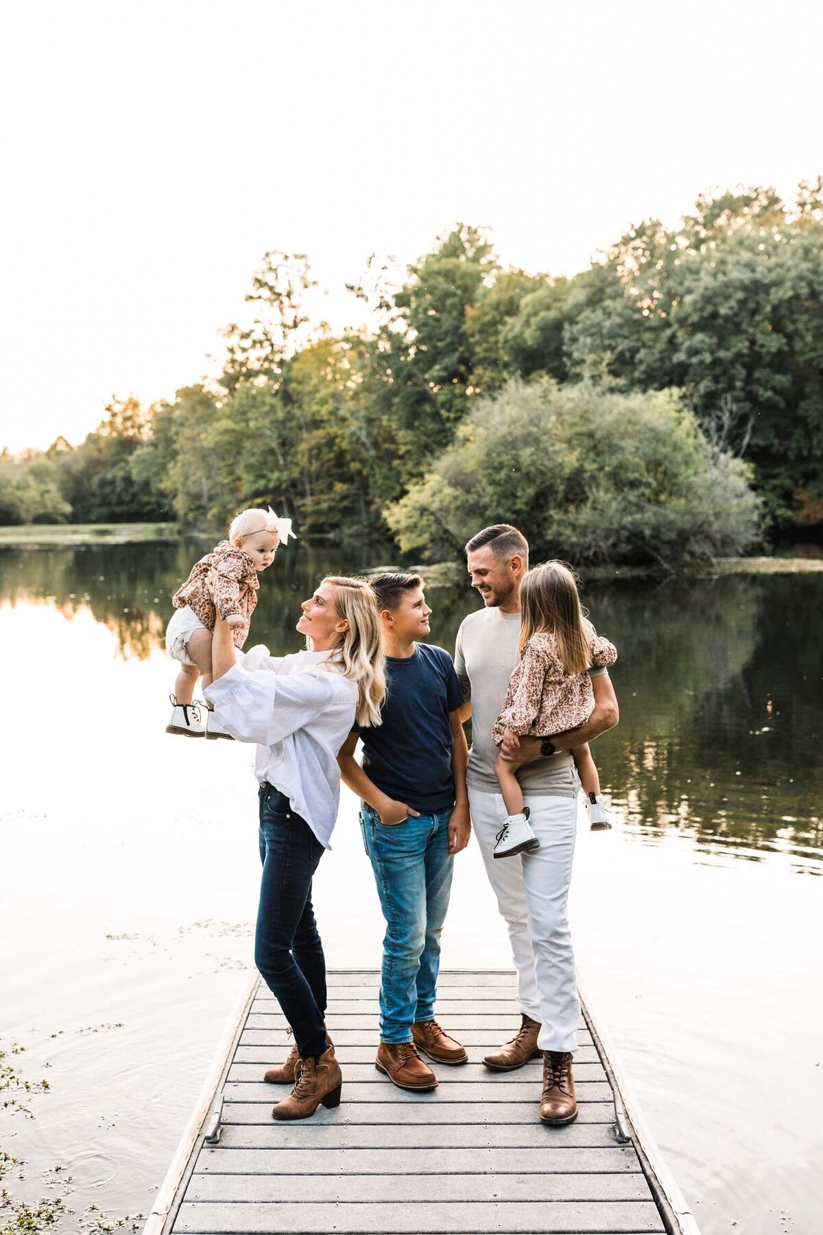 Family laughing and standing together on a dock by a peaceful lake during a South Bend session.